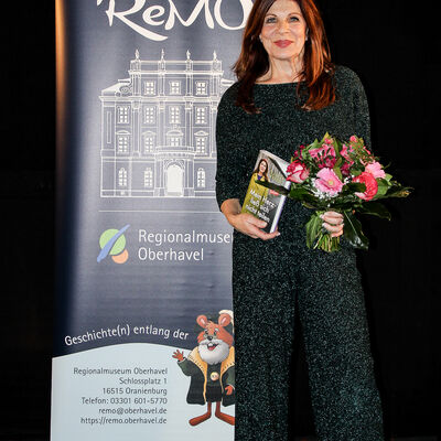 Claudia Wenzel mit ihrem Buch und einem Strauß Blumen in der Hand