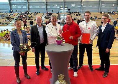 Vor dem Start des Zweifelderballturniers: Der Vorsitzende des Fördervereins für Schulsport, Uwe Peter (3. von links), und Olaf Neupert (4. von links), Filialdirektor Oranienburg der Mittelbrandenburgischen Sparkasse, unterzeichneten am Donnerstag in der MBS-Arena den 24. Kooperationsvertrag. Mit dabei waren Schulrätin Colette Wawer (v.li.), Oberhavels Dezernent für Bildung, Kultur und Sport, Holger Mittelstädt, und der für die Finanzen des Fördervereins zuständige Maximilian Pade sowie Kay Duberow, Geschäftsführer der TURM Erlebniscity Oranienburg.